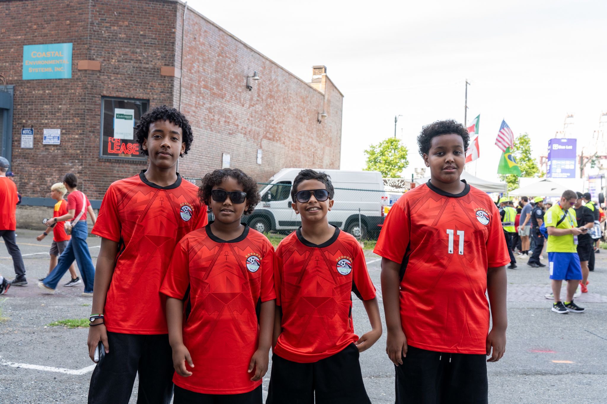Four East African youth wearing red jerseys stand in a city street
