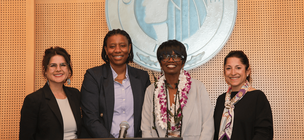 Four women standing together under the City of Seattle crest