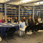 A group of young people sitting around a long table in discussion