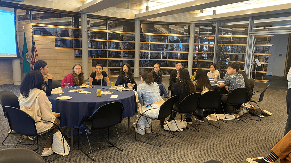 A group of young people sitting around a long table in discussion
