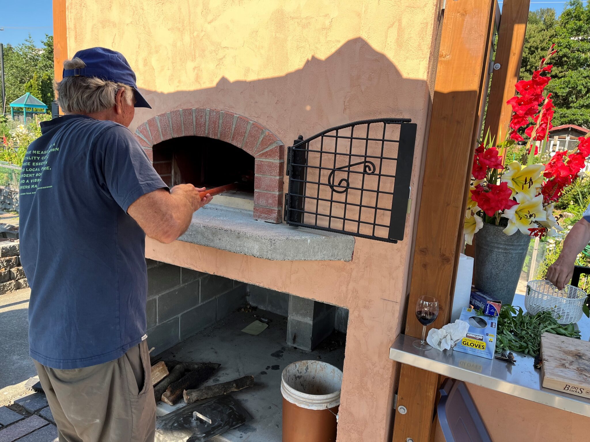 A person tending a pizza oven in a community garden.