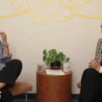 Two Vietnamese women sitting in a comfortable room with a lotus painted on the wall behind them
